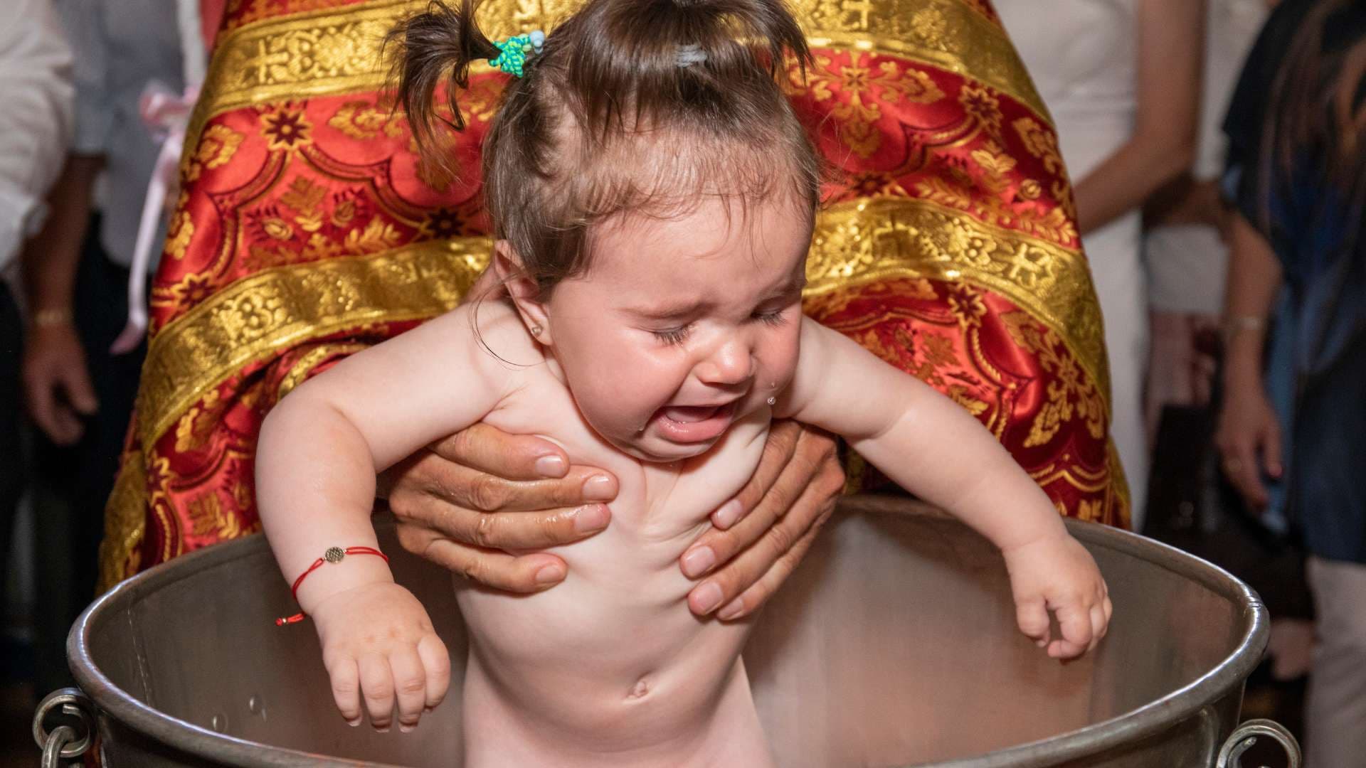 Бебе в купела по време на кръщенето